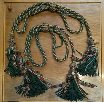 a picture of a green and white rope with tassels on it