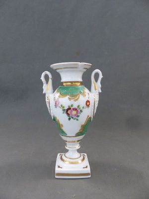 un vase blanc orné d'un motif floral, posé sur un socle