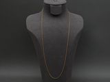a mannequin with a gold chain on a black background