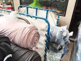 many rolls of fabric on a cart outside of a store