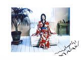 a picture of a woman sitting on a bed in a room