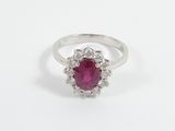 a close up of a ring with a ruby stone surrounded by white diamonds