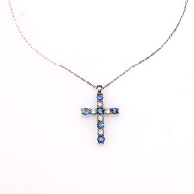 un pendentif en forme de croix, orné de diamants bleus et blancs, monté sur une chaîne en argent