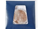 a close up of a coin in a package on a white surface