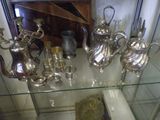 a glass display case with many silver items on it