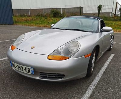 silver sports car parked in a parking lot in front of a building