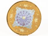 une assiette en or ornée d'une fleur violette