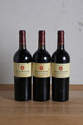 trois bouteilles de vin rouge posées sur une table en bois, à côté d'une bouteille de vin
