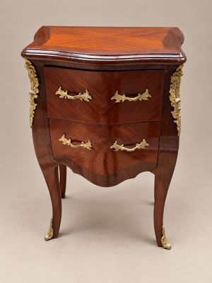 une commode ancienne ornée de détails dorés et dotée d'un plateau en bois