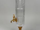 a glass water dispenser with a gold faucet on it