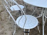 a white table and four chairs outside in the yard