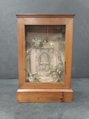 une vieille photo représentant un cadre en bois dans lequel figure le portrait d'une femme sur le seuil d'une porte