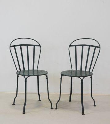 pair of black metal chairs with green seats against a white wall