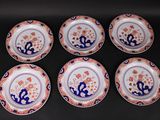 six plates with blue and orange designs on them sitting on a black surface