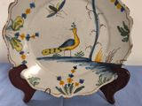 a plate with a peacock on it sitting on a table