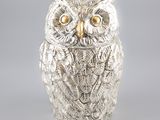 une photo d'une figurine de chouette en argent posée sur une table