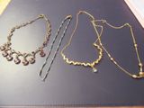 three necklaces and a bracelet sitting on a table