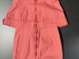 a pink dress with ruffles on the shoulders and a black purse