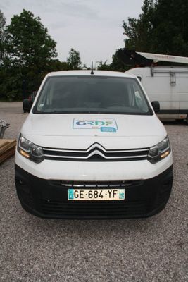 une camionnette blanche garée sur un parking, avec une remorque en arrière-plan