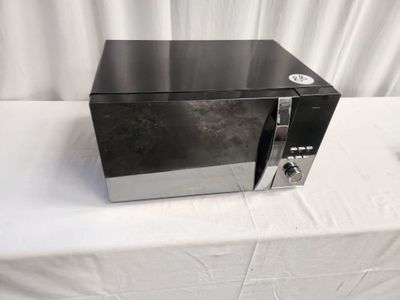a black microwave sitting on a table with a white table cloth
