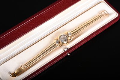 une montre en or dans un coffret rouge posé sur une surface noire