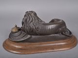 bronze statue of a lion on a wooden base with a candle