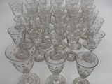 twelve clear wine glasses are lined up on a white surface