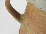 a brown vase with a handle on a white surface