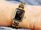 a woman wearing a gold and black watch on her wrist