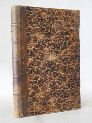 an old book sitting on top of a table next to a white wall