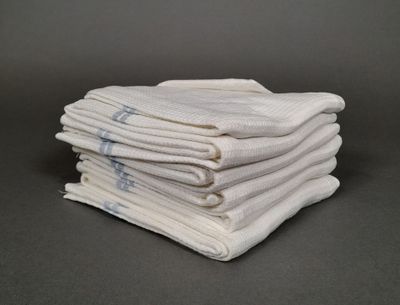 plusieurs serviettes blanches empilées les unes sur les autres sur une table
