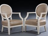pair of white chairs with beige upholstered cushions on a black background