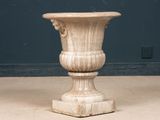 a stone vase sitting on the floor in front of a blue wall