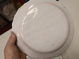 a person holding a white plate on a table