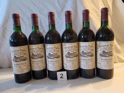 Six bouteilles de vin sont alignées sur une table blanche.