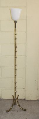a tall brass floor lamp with a glass shade on it