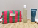 un sac rose et vert posé sur une table à côté d'un flacon de lotion