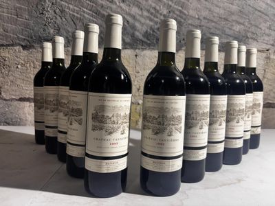 several bottles of wine are lined up on a table in front of a stone wall