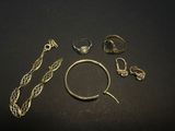 several gold rings and bracelets laid out on a black surface