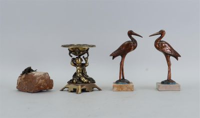 trois statues d'oiseaux en bronze et un rocher posés sur une table