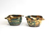 pair of green and gold vases sitting on a white surface