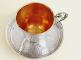 a silver cup and saucer on a saucer
