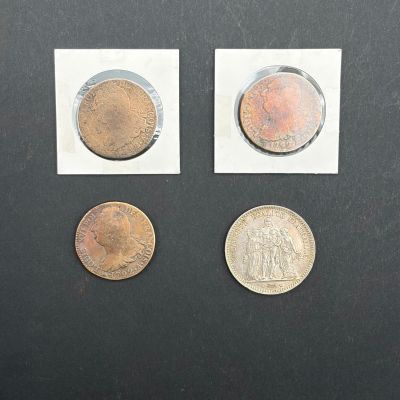 Trois pièces différentes sont représentées sur une surface noire ; l'une d'entre elles est un penny et l'autre est une