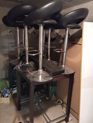quatre tabourets noirs posés sur une table en métal