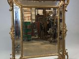 une image représentant un miroir à cadre doré posé sur un sol blanc