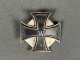 une broche en forme de croix de fer surmontée d'une couronne, posée sur une table