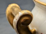 a white vase with a gold handle on a table