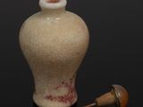 a picture of a small white vase with a red spot on it