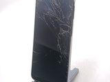 a broken cell phone sitting on a stand on a white surface