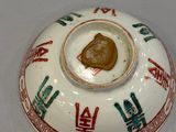 a white bowl with red and green designs on it
